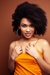 Fototapeta premium pretty young african american woman with curly hair posing cheerful gesturing on brown background, lifestyle people concept