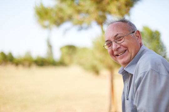 old man smiling with hearing aid and glasses outdoor