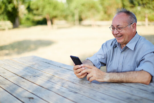 Smiling old man on video call with hearing aid outdoor