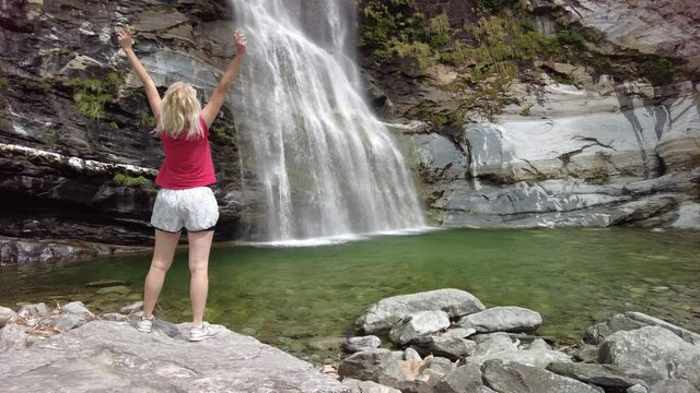 Woman running by the great waterfall of Bignasco, Valle Maggia, intersection point between the Bavona valley and Lavizzara valley, Cevio in Switzerland.