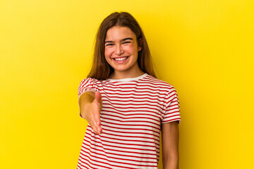 Obraz premium Young caucasian woman isolated on yellow background stretching hand at camera in greeting gesture.