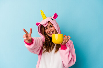 Young caucasian woman wearing an unicorn costume holding a mug isolated