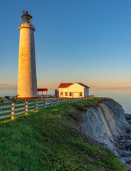 View at sunset on the Atlantic ocean, the cliffs and the Cap Des Rosiers lighthouse, the highest lighthouse in Canada, located near Forillon National Park in Quebec