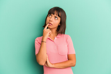 Young mixed race woman isolated on blue looking sideways with doubtful and skeptical expression.