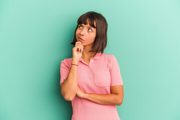 Young mixed race woman isolated on blue looking sideways with doubtful and skeptical expression.