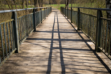 Naklejka na ściany i meble Bridge with wooden floor and green metal railing in the park