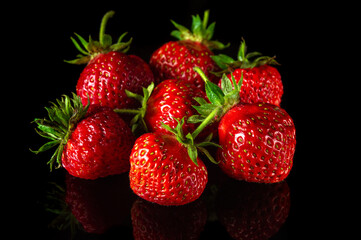 A lot of red ripe strawberries on a black background. Summer diet and vitamin set idea