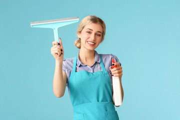 Young woman with detergent and squeegee on color background