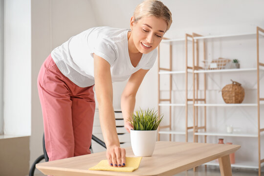 Young Woman Cleaning Table In Her Flat