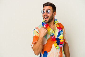 Young caucasian man dancing on a hawaiian party isolated on white background points with thumb finger away, laughing and carefree.