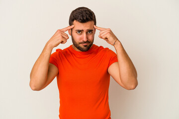 Young caucasian man isolated on white background focused on a task, keeping forefingers pointing head.