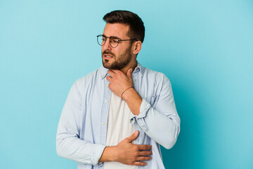 Young caucasian man isolated on blue background suffers pain in throat due a virus or infection.