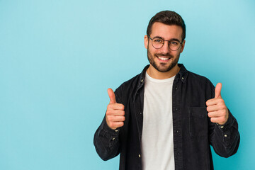 Young caucasian man isolated on blue background smiling and raising thumb up
