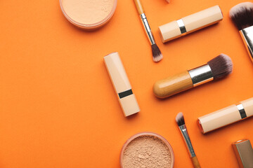 Decorative cosmetics and makeup brushes on color background