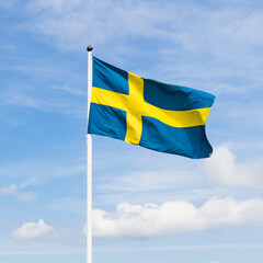 Swedish flag with cloudy sky background.