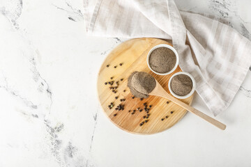 Board with black pepper powder on light background