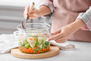 Woman cooking tasty soup in kitchen