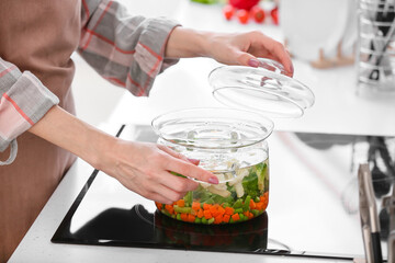 Woman cooking tasty soup on stove in kitchen