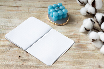 White notepad for notes. Template for writing. Cotton and candle on a wooden table. Top view, flat lay.