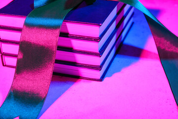 Stack of books with ribbon on dark color background, closeup