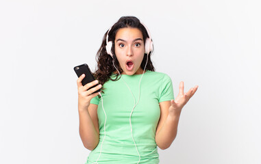 pretty hispanic woman amazed, shocked and astonished with an unbelievable surprise with headphones...