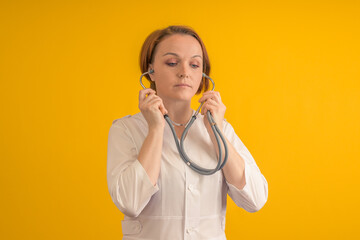 A woman doctor puts on a stethoscope. On a yellow background.