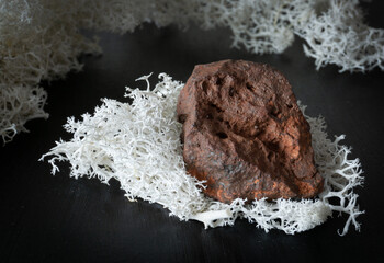 Goethite from Morocco. Natural mineral stone on a black background surrounded by moss. Mineralogy, geology, magic, semi-precious stones and samples of minerals. Close-up macro photo
