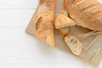 Board with fresh bread on white wooden background