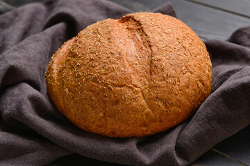 Loaf of wholegrain bread on dark wooden background