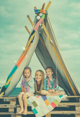 Obraz premium Mom parent with children daughter together. Playing in tent. Family camping. Mom with kids having fun outdoors. Vacation concept. Mothers day.