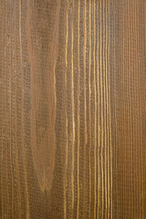 The texture of a wooden board as a natural background. Vertical location. Wooden background in a pleasant brown-gold color scheme