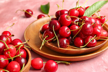 Bowls with tasty ripe cherry on color background, closeup