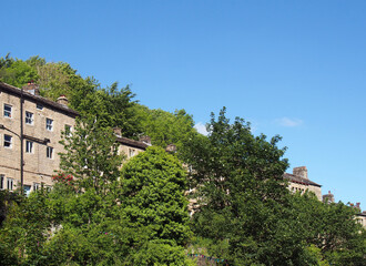 Fototapeta na wymiar a row of traditional tall houses on a hillside surrounded by trees in summer in hebden bridge west yorkshire