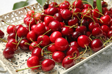 Tray with tasty ripe cherry on light background, closeup