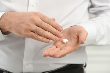 Fototapeta premium Man applying cream onto hand on blurred background, closeup