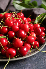 Plate with tasty ripe cherry on dark background, closeup