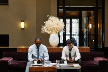 Front view at two business people discussing deal in hotel lounge