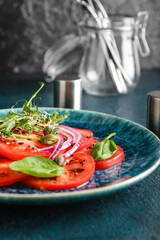 Plate with tasty tomato carpaccio on dark background