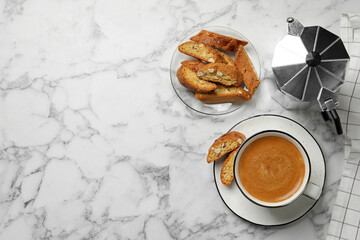 Flat lay composition with tasty cantucci and aromatic coffee on white marble table, space for text....