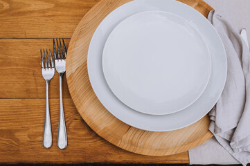 Cutlery, silverware, cutlery on a wooden table: white plate, fork, knife. Photography, concept.