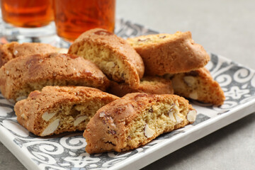 Tray with tasty cantucci and glasses of liqueur on light table, closeup. Traditional Italian almond biscuits