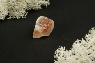 Halite or rock salt from Pakistan. Natural mineral stone on a black background surrounded by moss. Mineralogy, geology, magic, semi-precious stones and samples of minerals. Close-up macro photo