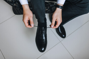 A man, a businessman ties long shoelaces on leather black shoes with his hands in a jacket...
