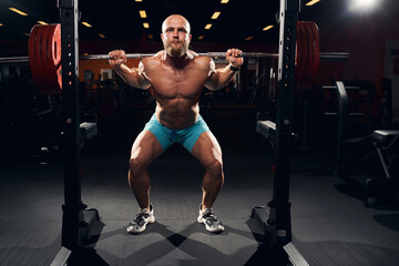 Fototapeta na wymiar Muscular sportsman squatting with a barbell on his shoulders
