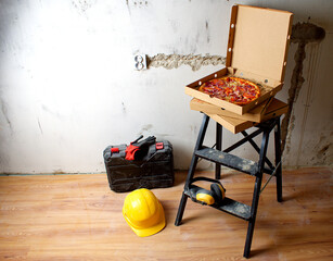Pizza for lunch on the stairs. Take a break from work. Black ladder, hard hat, ear protectors,...