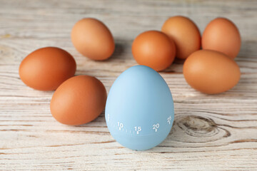 Kitchen timer and eggs on white wooden table