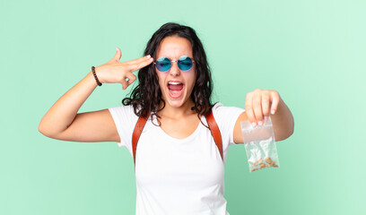 hispanic pretty woman looking unhappy and stressed, suicide gesture making gun sign and holding a...