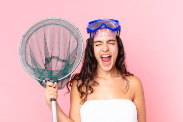 pretty hispanic woman shouting aggressively, looking very angry with goggles and fishing net