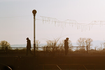 two people walk in different directions along the river embankment