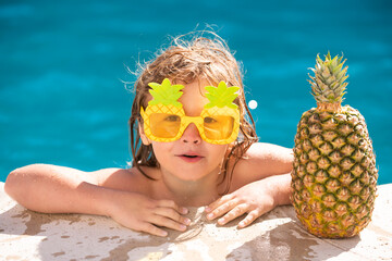 Happy child having fun at swimming pool on sunny day. Kids summer holidays and vacation concept. Summer pineapple fruit.